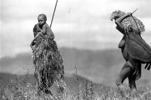 Samuel Putnam negatives, New Guinea; 2 women walking in the fields; one has a child on her shoulders