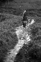 Samuel Putnam negatives, New Guinea; a young girl walking on salt trail; northward past Homoak; muddy