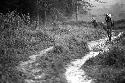 Samuel Putnam negatives, New Guinea; couple of people using the trail outside of Homoak