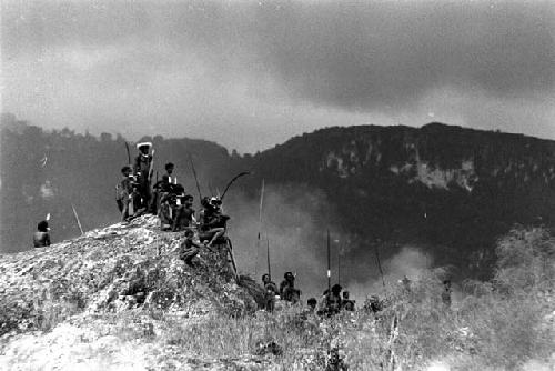 Samuel Putnam negatives, New Guinea; a view along the Warabara; men seated on the rocks of the Warabara eastern ridge rising behind them