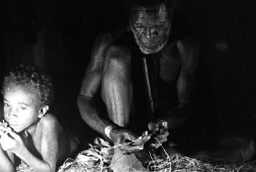 Samuel Putnam negatives, New Guinea; an old man; it is Yai-i; and Yege Abu; Yai-i is making; Yege Abu is simply lying down on the floor of the honai at Homaklep