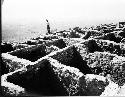 Man standing next to excavated building foundations at Awatovi