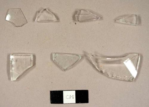 Colorless curved glass fragments, including one tumbler rim fragment and one possible fragment from a hurricane lamp