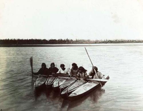 Inuit people sitting in kayaks