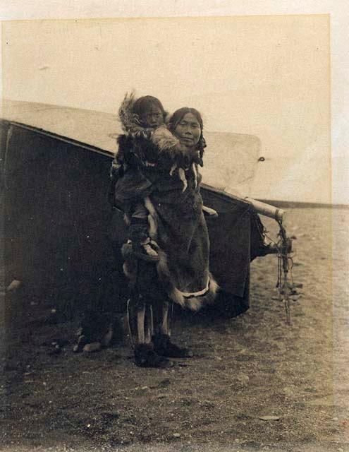Inuit woman carrying child on her back