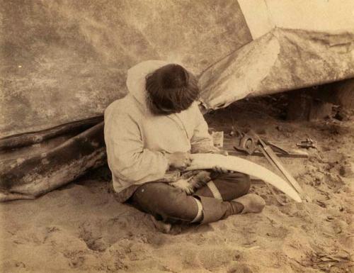 Inuit man carving bone