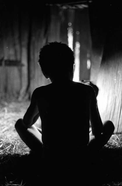 Samuel Putnam negatives, New Guinea; Uwar from behind;  the light making him a silhouette inside the honai