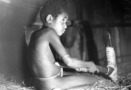 Samuel Putnam negatives, New Guinea; Uwar looking at a huge stone axe of Weaklekek