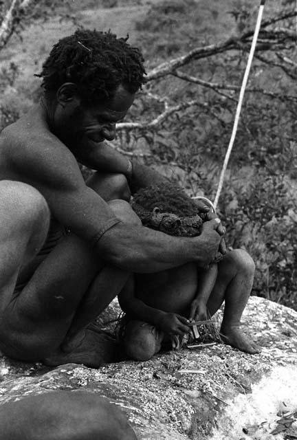 Samuel Putnam negatives, New Guinea; a man and his little girl; he holds her closely in front of him; on the Anelerak