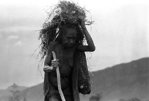 Samuel Putnam negatives, New Guinea; an old woman puts a net on her back