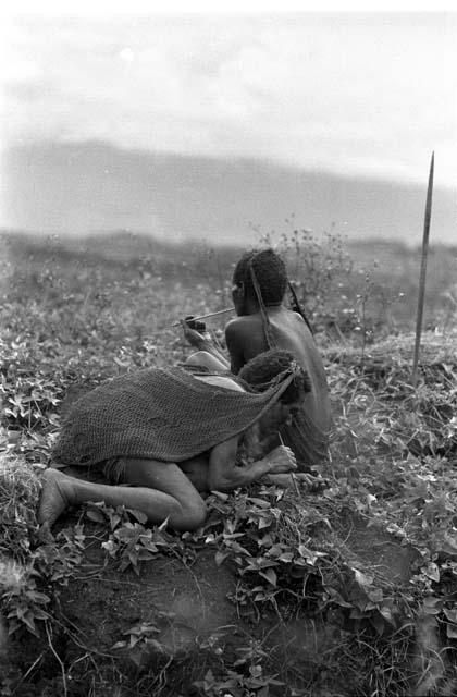 Samuel Putnam negatives, New Guinea; three women sitting; resting in the fields; one is trying to light a cigarette from a grass bundle