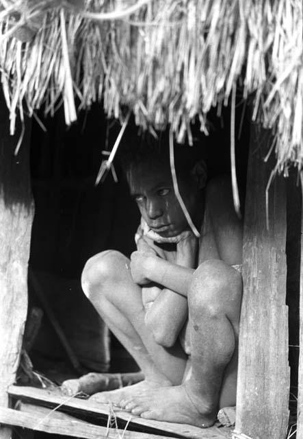 Samuel Putnam negatives, New Guinea; boy sitting on his ebeai; early morning