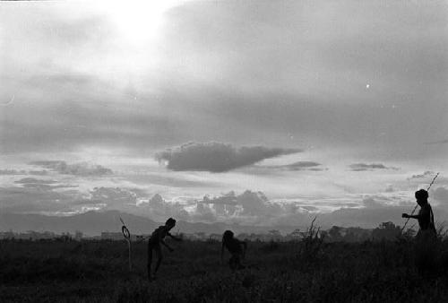 Samuel Putnam negatives, New Guinea; boys silhouetted; playing sikoko wasin; in the distance