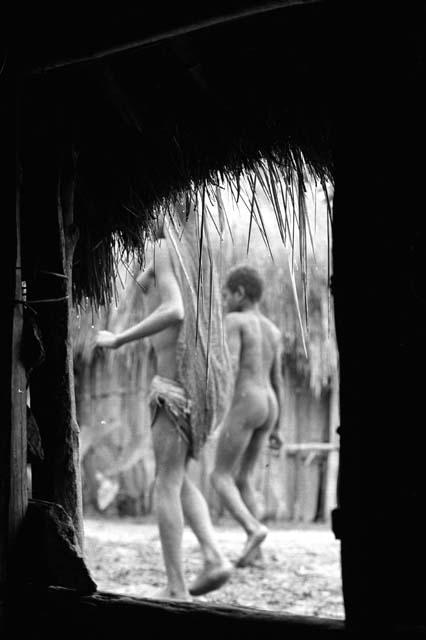 Samuel Putnam negatives, New Guinea; people walking outside hunu in Wuperainma