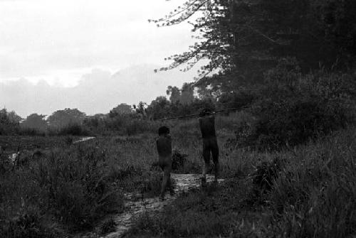 Samuel Putnam negatives, New Guinea; a boy and a man walking in front of Homoak going north