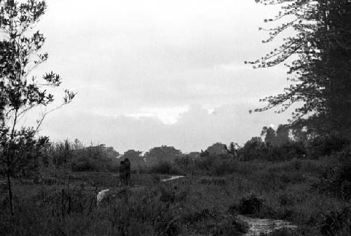 Samuel Putnam negatives, New Guinea; a boy and a man walking in front of Homoak going north