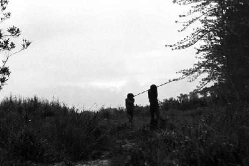 Samuel Putnam negatives, New Guinea; a boy and a man walking in front of Homoak going north