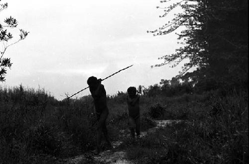 Samuel Putnam negatives, New Guinea; a boy and a man walking in front of Homoak going north