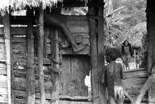 Samuel Putnam negatives, New Guinea; children climbing on the entryway to Wuperainma I; woman in the sili beyond