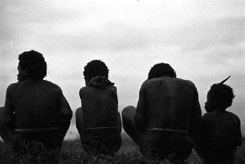 Samuel Putnam negatives, New Guinea; backs of 4 people sitting on the trail outside of Homoak