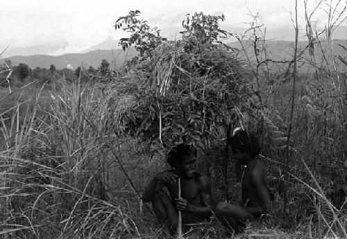 Samuel Putnam negatives, New Guinea; 2 warriors under a rain shelter on the Tokolik