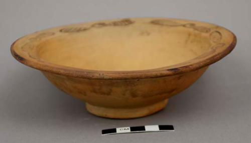 Footed ceramic bowl with flat rim; painted stylized floral pattern on rim; painted rim edge