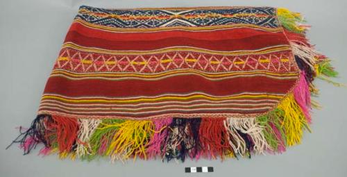 Poncho; red ground with wide patterned bands in black, pink, yellow, green and white