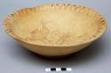 Footed ceramic bowl with curved rim; interior of bowl painted with striped triangles at rim and four birds in center; three large rim chips