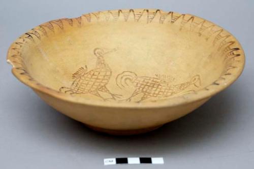 Footed ceramic bowl with curved rim; interior of bowl painted with striped triangles at rim and four birds in center; three large rim chips