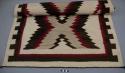 Navajo rug with central intertwined double diamond design, white background, gray, black and red wool