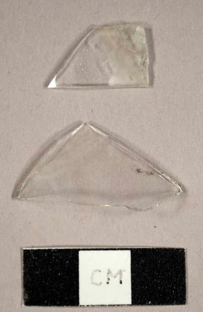 Colorless curved glass fragments, possibly from a hurricane lamp and one possibly melted