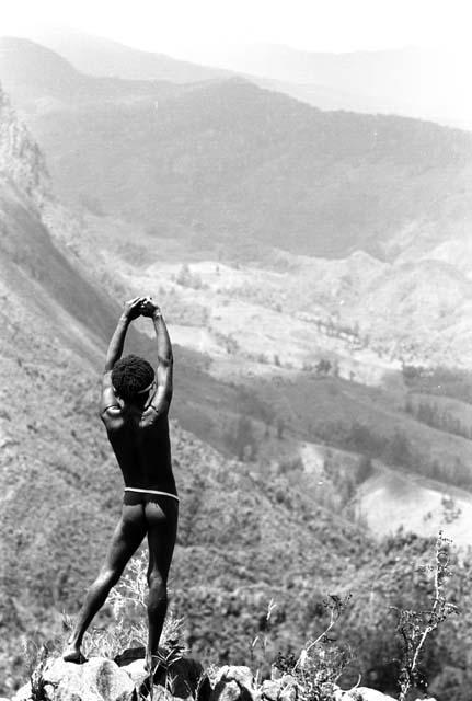 Samuel Putnam negatives, New Guinea; young man looking towrds the Solimo; hands above head; valley stretching out below him