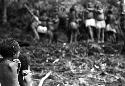 Samuel Putnam negatives, New Guinea; 2 little children in the frgd in focus; dancers completely out of focus in the bkgd