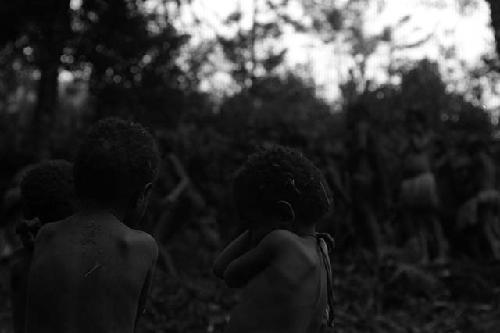 Samuel Putnam negatives, New Guinea; 2 little children in the frgd in focus; dancers completely out of focus in the bkgd