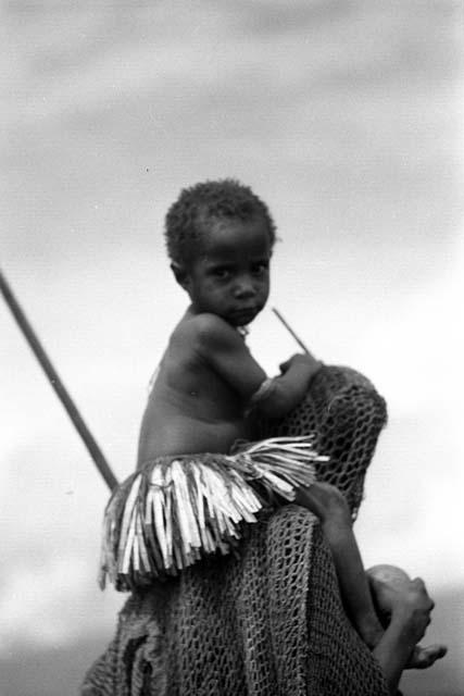 Samuel Putnam negatives, New Guinea; woman with child on her shoulders; child looks at the camera