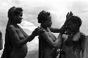 Samuel Putnam negatives, New Guinea; 2 women and 1 girl putting on clay