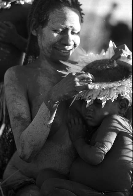 Samuel Putnam negatives, New Guinea; a woman fixes a kaia kara on a little boy's head