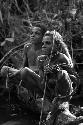 Samuel Putnam negatives, New Guinea; Okal and Isile perched on a log near the Elokhere River; equipped to play sikoko wasin; these are twin boys