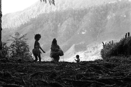 Samuel Putnam negatives, New Guinea; woman and child; silhouette- walking out onto the lighter part near the woods that go down to the Elokhere