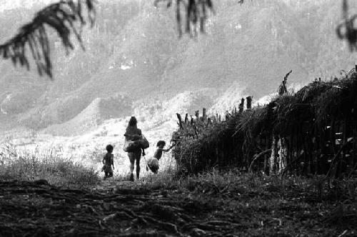 Samuel Putnam negatives, New Guinea; woman and child; silhouette- walking out onto the lighter part near the woods that go down to the Elokhere