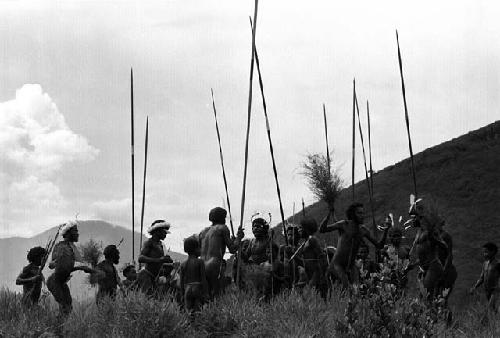 Samuel Putnam negatives, New Guinea; group of people going to the Etai; about 20 boys and men and spears; dancing near the Anelerak; Tukumba in background