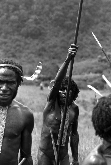 Samuel Putnam negatives, New Guinea; three men dancing; one man singing; holding his high up with a spear