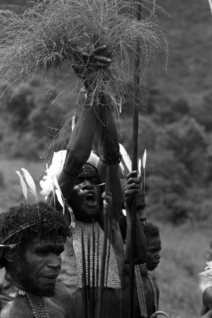 Samuel Putnam negatives, New Guinea; three men dancing; one man singing; holding up two grass tassels in the air