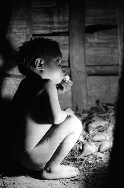 Samuel Putnam negatives, New Guinea; small boy eating inside of hunu