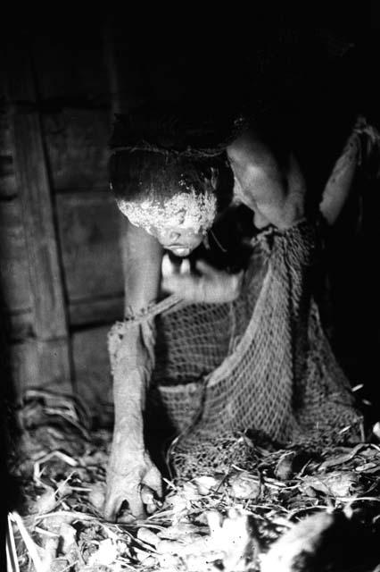 Samuel Putnam negatives, New Guinea; a woman throwing things into her su from the hakse