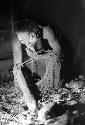 Samuel Putnam negatives, New Guinea; a woman throwing things into her su from the hakse