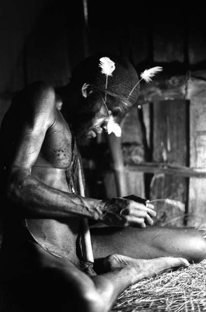 Samuel Putnam negatives, New Guinea; Wali in his honai in Lokoparek; putting feathers into his hair net