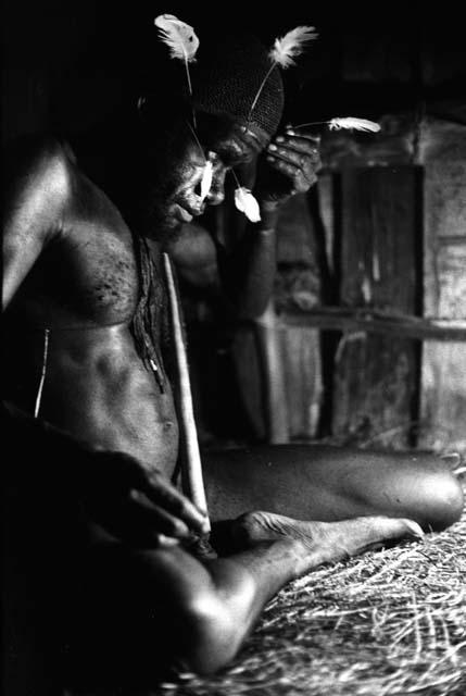Samuel Putnam negatives, New Guinea; Wali in his honai in Lokoparek; putting feathers into his hair net
