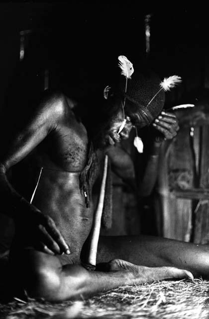 Samuel Putnam negatives, New Guinea; Wali in his honai in Lokoparek; putting feathers into his hair net