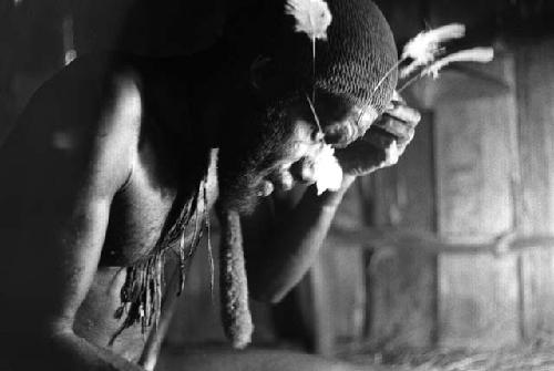 Wali in his honai in Lokoparek; putting feathers into his hair net